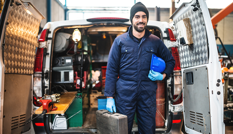 CRC HNOA - Man with hard hat in front of work van with tools.